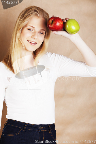 Image of young pretty blond woman choosing between red and green apple sm