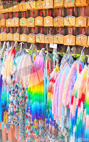 Image of Ema prayer tablets and strings of paper origami cranes. Wishes written in Japanese on the plaques.