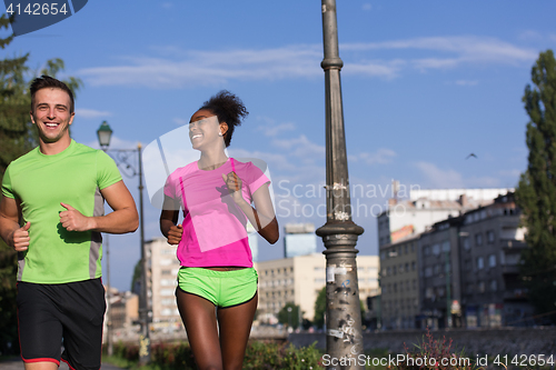 Image of young smiling multiethnic couple jogging in the city