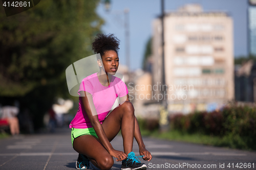 Image of African american woman runner tightening shoe lace