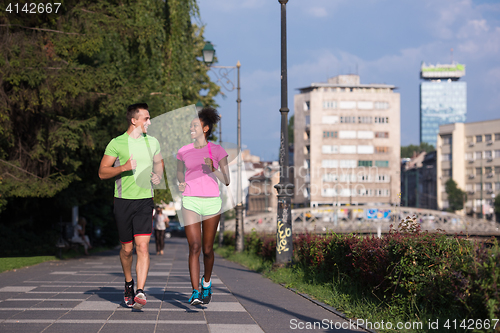 Image of young smiling multiethnic couple jogging in the city