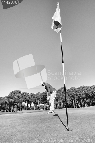 Image of golf player hitting shot with club on course