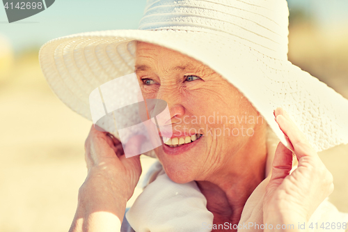 Image of happy senior woman in sun hat on summer beach