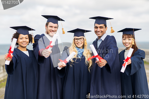 Image of happy students in mortar boards with diplomas