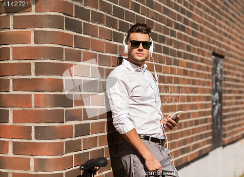 Image of man with headphones, smartphone and bicycle