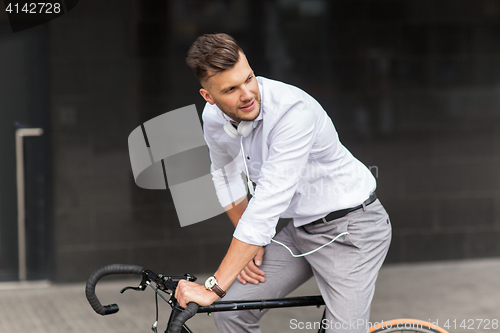 Image of man with bicycle and headphones on city street