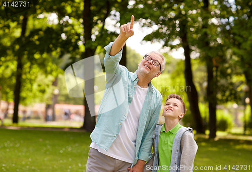 Image of grandfather and boy pointing up at summer park