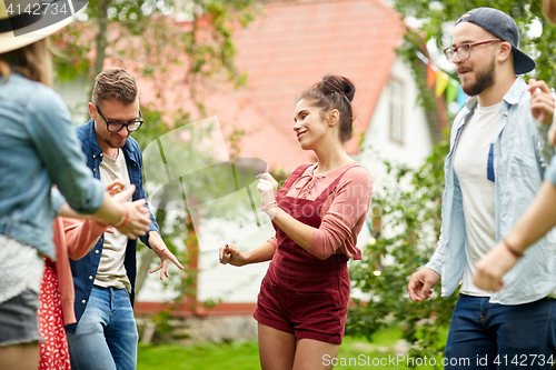 Image of happy friends dancing at summer party in garden