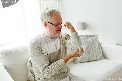 Image of unhappy senior man suffering elbow pain at home