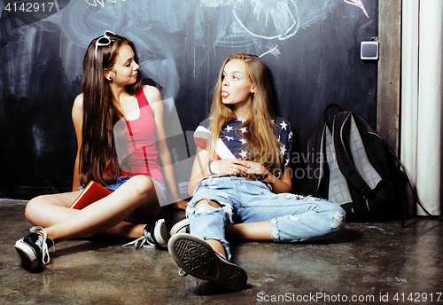 Image of back to school after summer vacations, two teen real girls in classroom with blackboard painted together