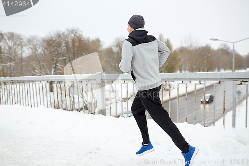 Image of man running along snow covered winter bridge road