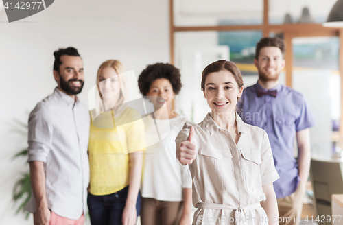 Image of woman showing thumbs up over creative office team