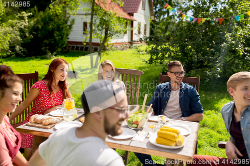 Image of happy friends having dinner at summer garden party