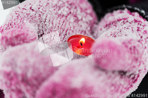 Image of close up of hands in winter mittens holding candle