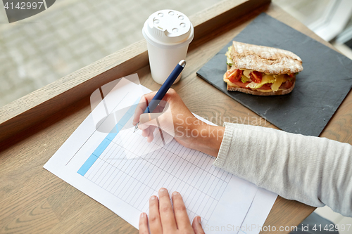 Image of woman with paper form having lunch at cafe