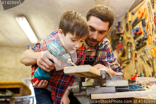 Image of father and son with drill working at workshop