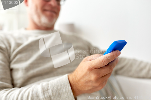 Image of close up of old man texting on smartphone at home