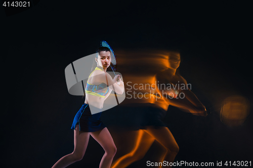 Image of Portrait of beautiful girl tennis player with a racket on dark background