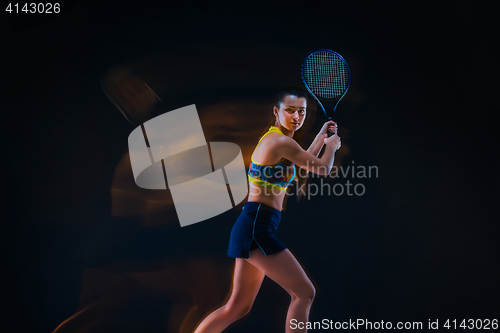 Image of Portrait of beautiful girl tennis player with a racket on dark background