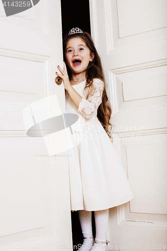 Image of little cute girl at home, opening door well-dressed in white dre