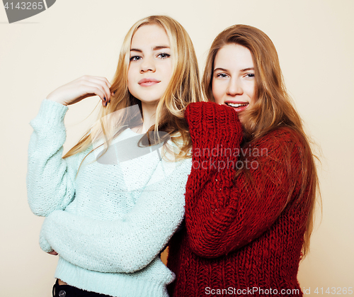 Image of Two young girlfriends in winter sweaters indoors having fun. Lif