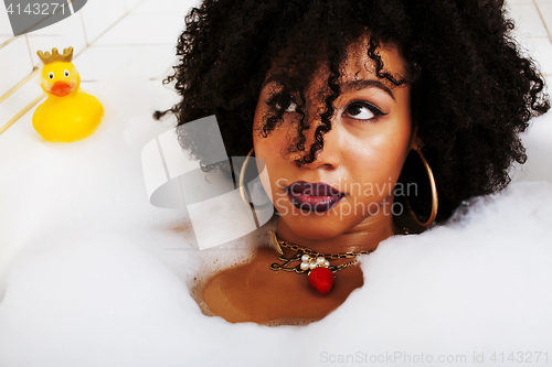 Image of young afro-american teen girl laying in bath with foam, wearing 