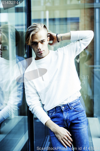 Image of young modern hipster guy at new building university blond fashio