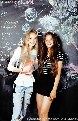 Image of back to school after summer vacations, two teen real girls in classroom with blackboard painted together