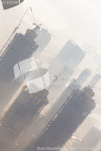 Image of Skyscrappers construction site with cranes on top of buildings.