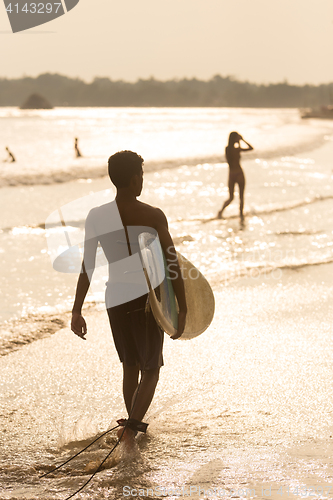 Image of Silhouette of surfer on beach with surfboard.