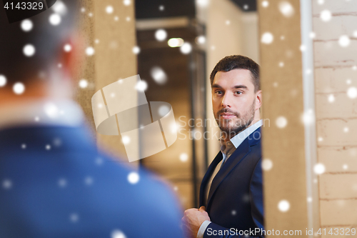 Image of man trying jacket on at mirror in clothing store