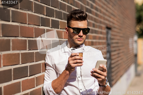 Image of man with smartphone and coffee cup on city street