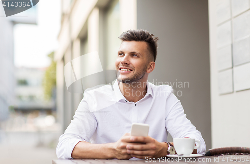 Image of man with smartphone and coffee at city cafe
