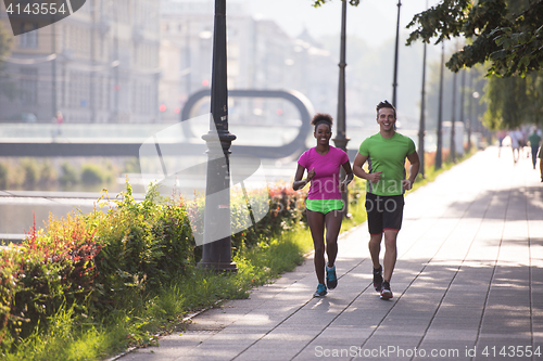 Image of young multiethnic couple jogging in the city
