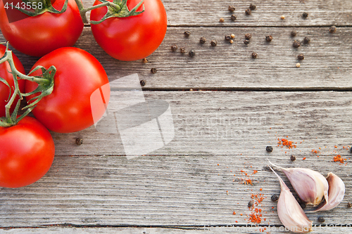 Image of Red tomatoes with pepper and garlic on old wood