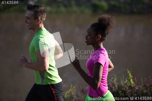 Image of young smiling multiethnic couple jogging in the city