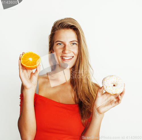 Image of young blonde woman choosing between donut and orange fruit isola