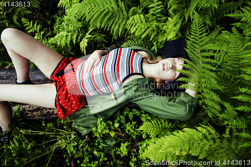 Image of Pretty young blond girl hipster in hat among fern, vacation in g