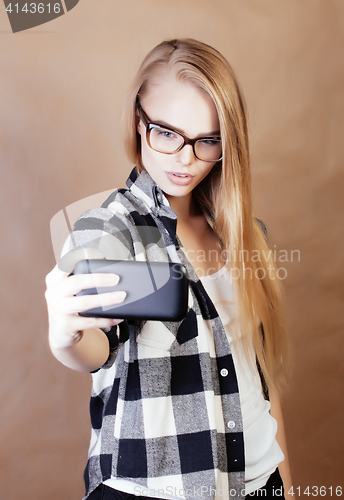 Image of young pretty blond hipster girl making selfie on warm brown background, lifestyle people concept