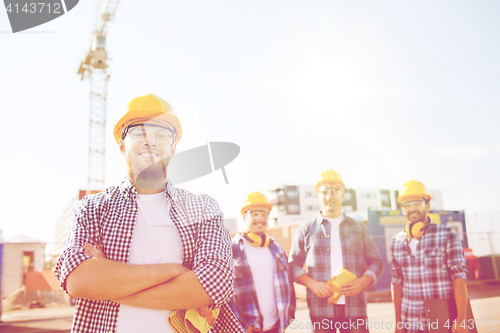 Image of group of smiling builders in hardhats outdoors