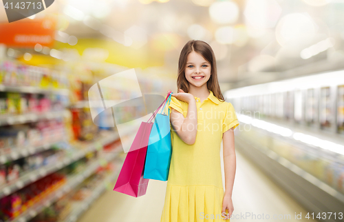 Image of smiling girl with shopping bags over supermarket