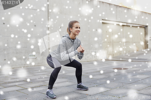 Image of happy woman doing squats and exercising outdoors