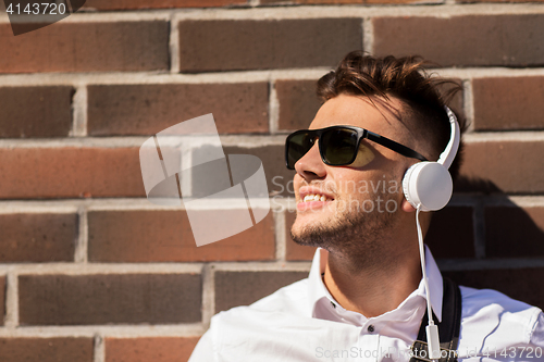 Image of young man in headphones over brickwall