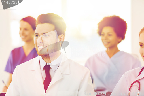 Image of happy doctor over group of medics at hospital