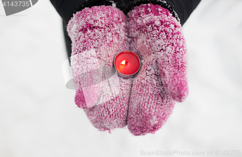 Image of close up of hands in winter mittens holding candle