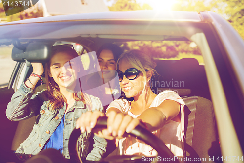 Image of happy teenage girls or young women driving in car