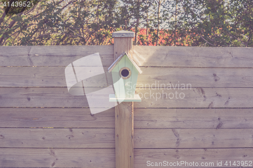 Image of Cute birdhouse on a wooden fence