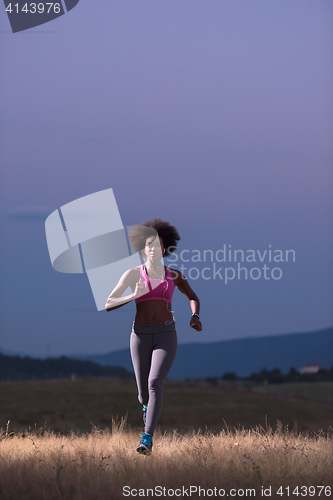 Image of Young African american woman jogging in nature