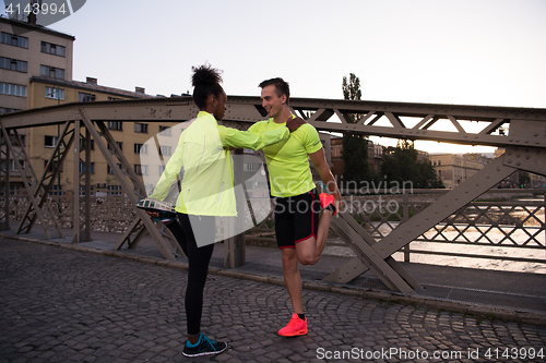 Image of jogging couple warming up and stretching in the city