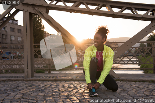 Image of African american woman runner tightening shoe lace